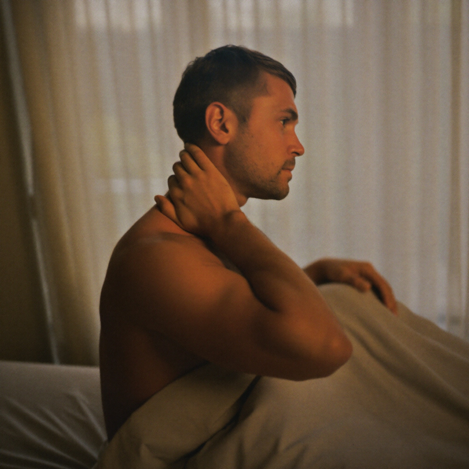 A man on the edge of his bed at dawn, thoughts still there